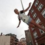 Boston, MA - 8/15/2017 - Ava Bonavita, 11, takes to the air as she is hoisted above North street in Boston's North End during a test run for the traditional 