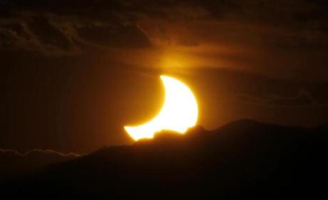 In this file photo, the solar eclipse is seen as the sun sets behind the Rocky Mountains from downtown Denver in May 2012.
