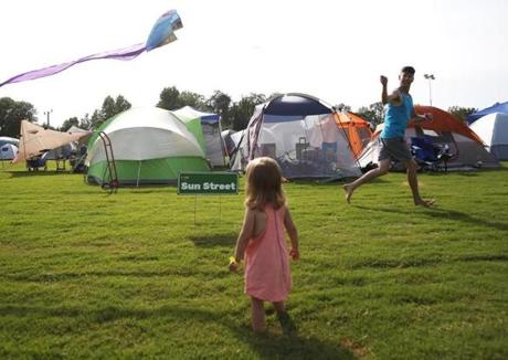 Hopkinsville, KY -- 8/19/2017 - Doug Gallagher, of Cincinnati, (R) runs with a kite for his two year-old daughter, Joy, down Sun Street at a makeshift campground in Hopkinsville city nearest the point of greatest eclipse. Gallagher and his family are camped out with others to watch tomorrow's eclipse. (Jessica Rinaldi/Globe Staff) Topic: 21EclipseNashville Reporter: Nestor Ramos
