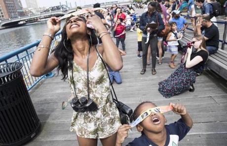 ECLIPSE SLIDE5 Boston, MA - 8/21/2017 - Krayonna Thames and her son Jaedin Barnes,5, use protective glasses to watch the solar eclipse along the waterfront near the Children's Museum in Boston, MA, August 21, 2017. (Keith Bedford/Globe Staff)
