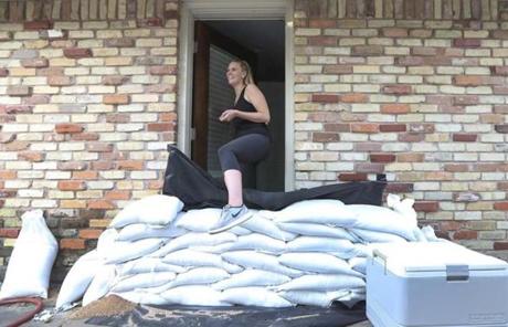 HARVEY SLIDER1 Lacey Williams exits the only door she can by stepping over sandbags that surround her home in Houston on Thursday, Aug. 24, 2017. Texas officials have been expressing concern that not as many people are evacuating compared with previous storms as Hurricane Harvey bears down on the state. (Steve Gonzales/Houston Chronicle via AP)
