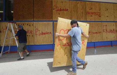 rd carries a sheet of plywood as he helps board up windows in preparation for Hurricane Harvey, Thursday, Aug. 24, 2017, in Corpus Christi, Texas. Two counties have ordered mandatory evacuations as Hurricane Harvey gathers strength as it drifts toward the Texas Gulf Coast. (AP Photo/Eric Gay)
