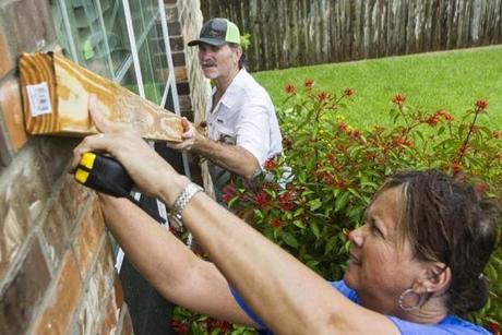 Amy Wuest, front, measures to make a cutting mark while Billy Broome helps hold the board on Friday, in Victoria, Texas. The two were boarding up windows in anticipation of Hurricane Harvey.
