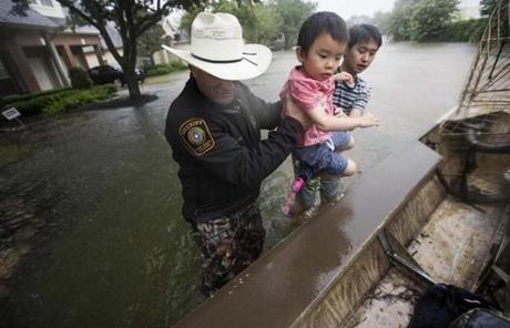 HARVEY SLIDER1 Fort Bend County Sheriff Troy Nehls and Lucas Wu lift Ethan Wu into an airboat as they are evacuated from rising waters from Tropical Storm Harvey, at the Orchard Lakes subdivision on Sunday, Aug. 27, 2017, in unincorporated Fort Bend County, Texas. (Brett Coomer/Houston Chronicle via AP)
