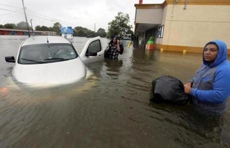 Conception Casa, center, and his friend Jose Martinez, right, check on Rhonda Worthington after her car became stuck in rising floodwaters from Tropical Storm Harvey in Houston, Texas, Monday, Aug. 28, 2017. The two men were evacuating their home that had become flooded when they encountered Worthington's car floating off the road. (AP Photo/LM Otero)

