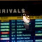 A woman is reflected in the arrivals board at Logan International Airport in Boston.