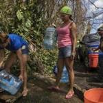 FILE -- Luz Rosado, center, directs the filling of water vessels at a natural spring at her home in Toa Alta, Puerto Rico, Sept. 25, 2017. The Trump administration, which has insisted that its efforts in Puerto Rico were adequate, faced increasing pressure on Sept. 28 to mount a more aggressive response to Hurricane MariaÕs devastating lashing of the island. (Victor J. Blue/The New York Times)