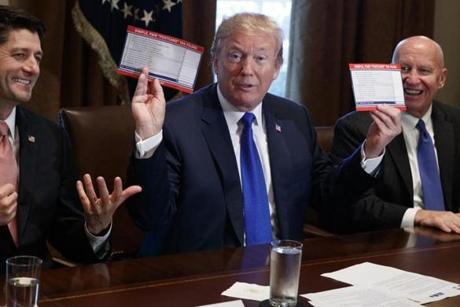 President Donald Trump holds an example of what a new tax form may look like during a meeting on tax policy with Republican lawmakers including House Speaker Paul Ryan of Wis., and Chairman of the House Ways and Means Committee Rep. Kevin Brady, R-Texas, right, in the Cabinet Room of the White House, Thursday, Nov. 2, 2017, in Washington. (AP Photo/Evan Vucci)
