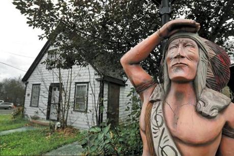 A carved wooden statue stands near a property in Sea Captains Row on Pleasant Street. A developer has proposed to tear down several 200-year-old neglected buildings for nine multifamily structures, pitting preservationists against some residents and business leaders.
