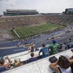 In this Sunday, Aug. 20, 2017 photo, fans take in views from the Duncan Student Center during open tours of Notre Dame Stadium during the New & Gold scrimmage game in South Bend, Ind. University officials offered the public on Sunday the chance to tour portions of the new buildings that now hug the stadium on three sides. The public also was invited to watch a scrimmage in the stadium, which features some new amenities, including a huge video board on the south end, attached to the new O'Neill Hall. (Michael Caterina/South Bend Tribune via AP)