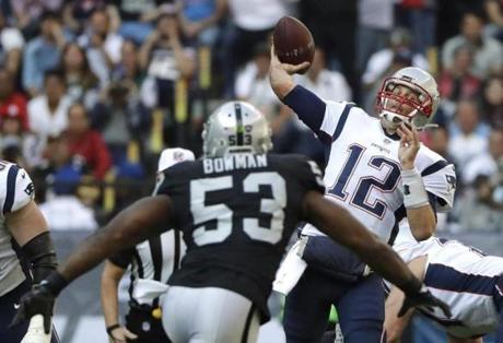 New England Patriots quarterback Tom Brady (12) passes under pressure from Oakland Raiders middle linebacker NaVorro Bowman (53) during the first half of an NFL football game Sunday, Nov. 19, 2017, in Mexico City. (AP Photo/Rebecca Blackwell)
