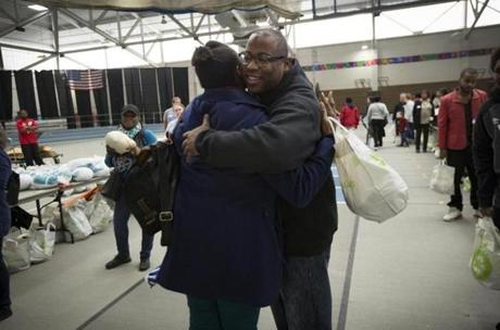 Outgoing City Councilor Tito Jackson hugs a woman who lined up for one of the 3,000 turkeys he gave away on Sunday to members of the community.
