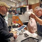 Mark Jaquith of Stillman Quality Meats handed over a turkey to Bill Koss of Newton on Wednesday.