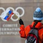 A woman holds a Russian flag in front of the Olympic Rings logo during the Executive Board meeting, at the International Olympic Committee (IOC) headquarters, in Pully near Lausanne, Switzerland, Tuesday, December 5, 2017. (Christophe Bott/Keystone via AP)