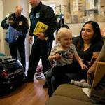 Sandra Cordero (right) held her son, Edison, as he admired gifts from members of the Chelsea Police Department that were brought to his home. Edison and his toddler-size cruiser are now honorary members of the force.  