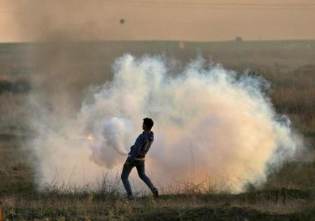 A Palestinian protester threw a tear gas canister back at Israeli forces during clashes near the Israel-Gaza border east of Gaza City on Saturday. 
