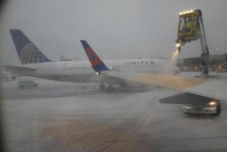 A Sun Country Airlines plane's wing is de-iced as a United Airlines plane waited at the de-icing station during a snowstorm at Logan International Airport in Boston in 2015.
