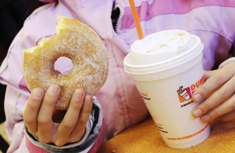 FILE - In this Thursday, Feb. 14, 2013, file photo, a girl has a doughnut and a beverage at a Dunkin' Donuts in New York. Dunkin' Brands reports financial earnings on Thursday, Feb. 4, 2016. (AP Photo/Mark Lennihan, File)
