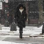 A woman walked through the snow as it falls in Boston Thursday.