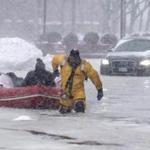 Boston firefighter Justin Plaza donned an ice rescue suit Thursday and used a raft to rescue a stranded driver and pull him to dry land.