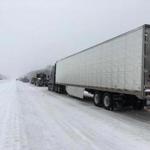 A line of semi-trucks, tow trucks and cars sits stationary on Interstate 40 westbound as road crews clear up an accident on Friday, Jan. 12, 2018, near Henderson, Tenn. The winter storm, which began with an icy mix before turning to snow, forced schools and businesses to close in Tennessee and Kentucky. Hardest hit were western parts of both states. (AP Photo/Adrian Sainz)