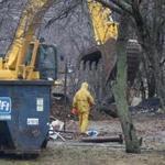 Investigators used a backhoe Tuesday to comb the area for evidence where a grisly double murder occurred last year.