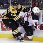 Boston Bruins left wing Brad Marchand (63) checks New Jersey Devils defenseman Will Butcher (8) into the boards during the second period of an NHL hockey game Tuesday, Jan. 23, 2018, in Boston. (AP Photo/Charles Krupa)
