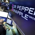 The Dr Pepper Snapple Group logo appears above a trading post on the floor of the New York Stock Exchange, Monday, Jan. 29, 2018. Keurig is buying Dr. Pepper Snapple Group Inc., creating a beverage giant with about $11 billion in annual sales. (AP Photo/Richard Drew)