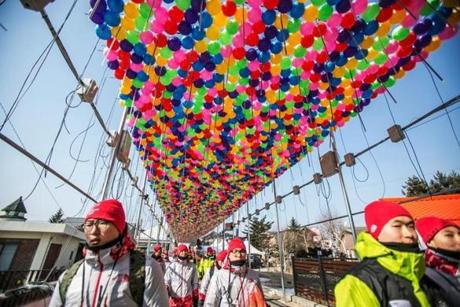 Olympic volunteers walked under Winter Olympics balloon decorations in PyeongChang, South Korea, on Thursday. 
