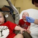 Kilian Daugherty, 1, got his nose cavity swabbed for the flu by emergency department technician Jake Weatherford as his sister Madison (left) waited to be examined as well for flu symptoms at Upson Regional Medical Center in Thomaston, Ga. last week.)