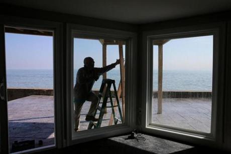 Marshfield, MA- March 01, 2018: Derek Affsa works on boarding up the windows on his home in the Brant Rock neighborhood of Marshfield, MA on March 01, 2018. He said he installed hurricane strength windows while renovating the home but he worries about the weight of the sand mixed with the waves in the coming storm. 