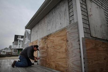 Jay Harvey worked to board up the windows of his home on Ocean Street in the Brant Rock neighborhood of Marshfield on Thursday.
