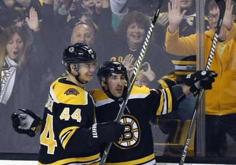 Boston Bruins' Brad Marchand, right, celebrates with teammate Nick Holden (44) after scoring the winning goal in overtime during an NHL hockey game against the Montreal Canadiens in Boston, Saturday, March 3, 2018. The Bruins won 2-1. (AP Photo/Michael Dwyer)
