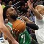 Jaylen Brown drives between the Minnesota Timberwolves' Nemanja Bjelica (left)  and Taj Gibson  in the first half. Brown had 14 points and 5 rebounds in 28 minutes before he left the game because of a hard fall.