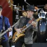 FILE - This May 3, 2014 file photo shows Nils Lofgren, center, performing with Bruce Springsteen and the E Street Band at the New Orleans Jazz and Heritage Festival in New Orleans. Lofgren as forged a relatively unique rock 'n' roll niche through a willingness to sublimate his ego and take on supporting roles with Springsteen, Neil Young and Ringo Starr in addition to writing and recording his own music. (AP Photo/Gerald Herbert, File)