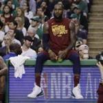Cleveland Cavaliers forward LeBron James sits on the scorer's table during a timeout in the first half in Game 2 of the team's NBA basketball Eastern Conference finals against the Boston Celtics, Tuesday, May 15, 2018, in Boston. At left is teammate JR Smith. (AP Photo/Charles Krupa)