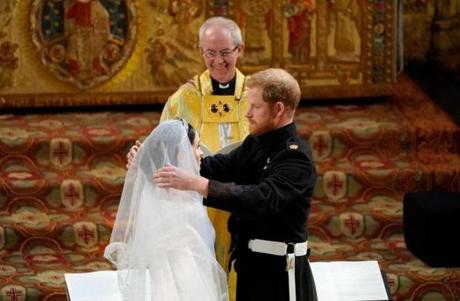 Britain?s Prince Harry removes the veil of Meghan Markle as they stand at the altar together.
