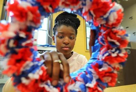 JROTC student Angel Clarke finished up the flowers on a Memorial Day wreath she was making in a classroom at the Community Academy of Science and Health.
