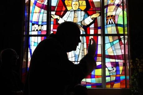 The Rev. Joseph Smyth, 89, prays in the chapel at the Regina Cleri residence for retired priests in Boston.. A stained- glass window depicting Pope Pius forms the backdrop.
