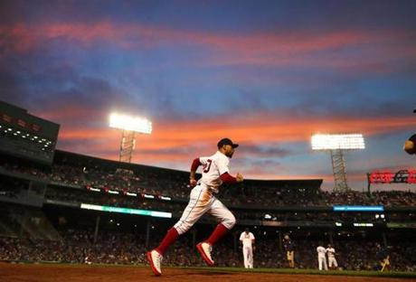 Mookie Betts runs to his position in right field as a brilliant sunset forms the backdrop at Fenway Park.
