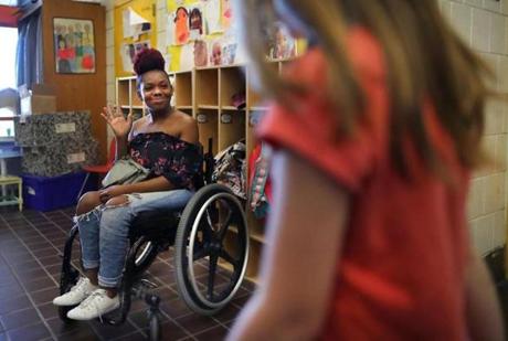 Boston- 05/24/18-Kai Leigh Harriott was paralyzed when she was shot by a stray bullet in the back when she was three years old in Roxbury. She waves to a student at the Josiah Quincy School where she works in an after school program with children who have special needs and handicaps. She once attended the school after she was shot. She just turned 18, and will be graduating in June from high school. Photo by John Tlumacki/Globe Staff Staff(metro)
