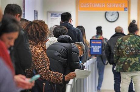 Boston, MA: 3/26/2018: In the early afternoon, people arriving at the Registry of Motor Vehicles office on Blackstone Street were being informed that their estimated wait time would be four hours. This is part of the line they waited in to get their number, then they would go into the waiting area and wait to have their number called. The large crowds were due to the implementation of the new Real ID driver's license system. (Jim Davis/Globe Staff)
