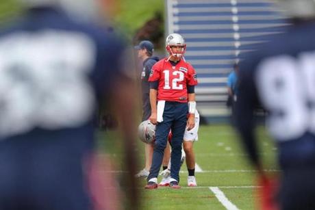 Foxborough- 06/05/18- The Patriots held a minicamp at the Gillette Stadium practice facility. QB Tom Brady is framed through players as he pauses during warmups. Photo by John Tlumacki/Globe Staff(sports)
