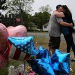 A couple embraced after leaving balloons at a memorial outside the home of Stewart Weldon.