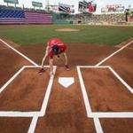 A member of the Fenway grounds crew put a final touchup of white paint on the batters box.