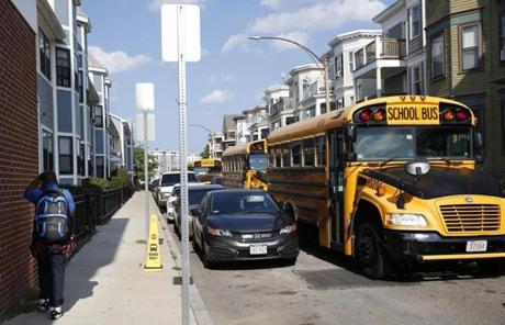 Dorchester, MA--8/29/2018-- A student walks down the sidewalk past school busses lined up outside of Codman Academy in Dorchester. (Jessica Rinaldi/Globe Staff) Topic: 30busses Reporter: 
