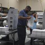 Election workers placed ballots into electronic counting machines.  