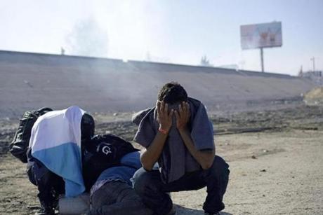 Three Honduran migrants huddle in the riverbank amid tear gas fired by US agents on the Mexico-US border on Sunday.
