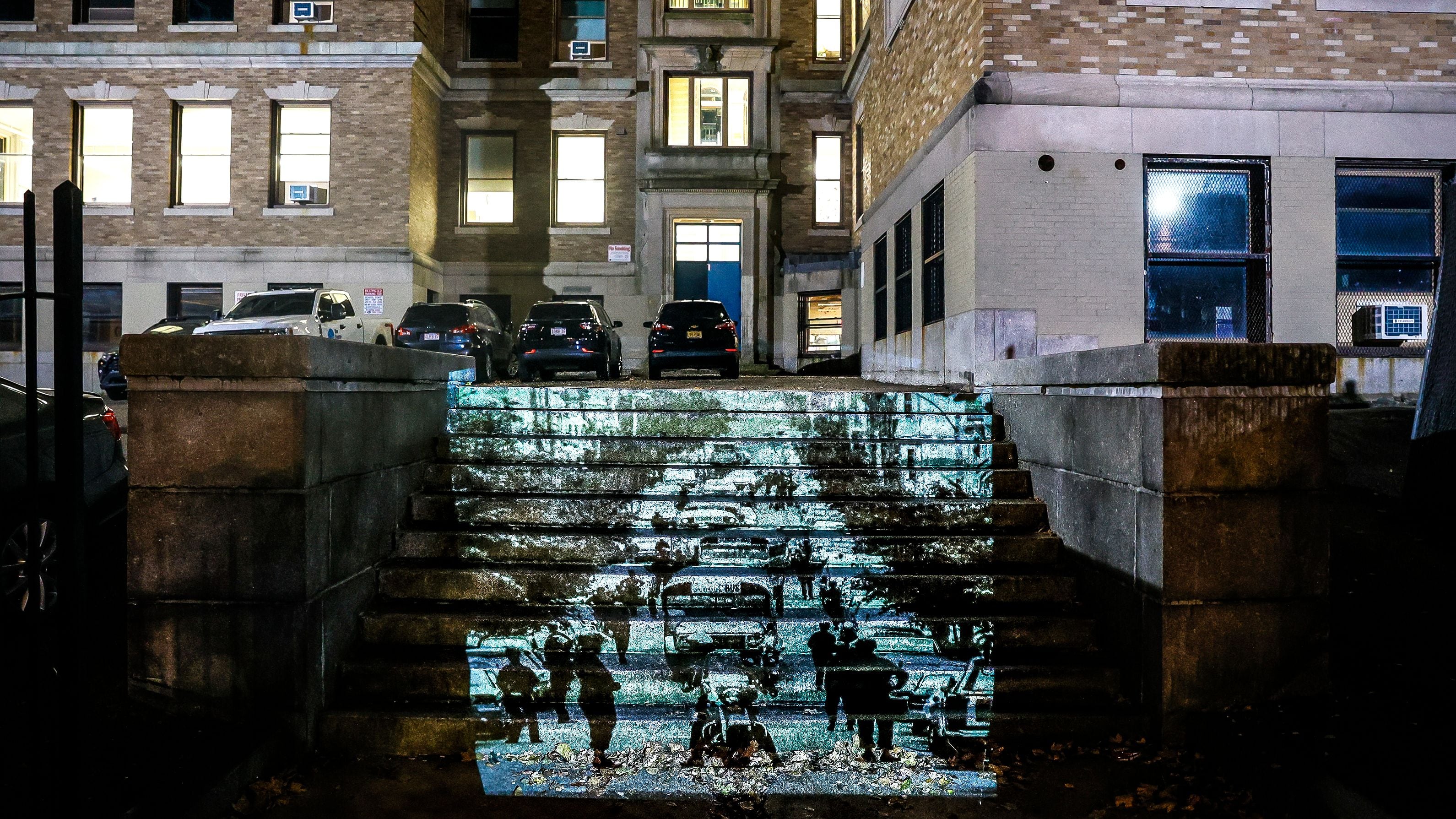 DonJuan Moses poses for a portrait next to a projection of police cars in Mission Hill 