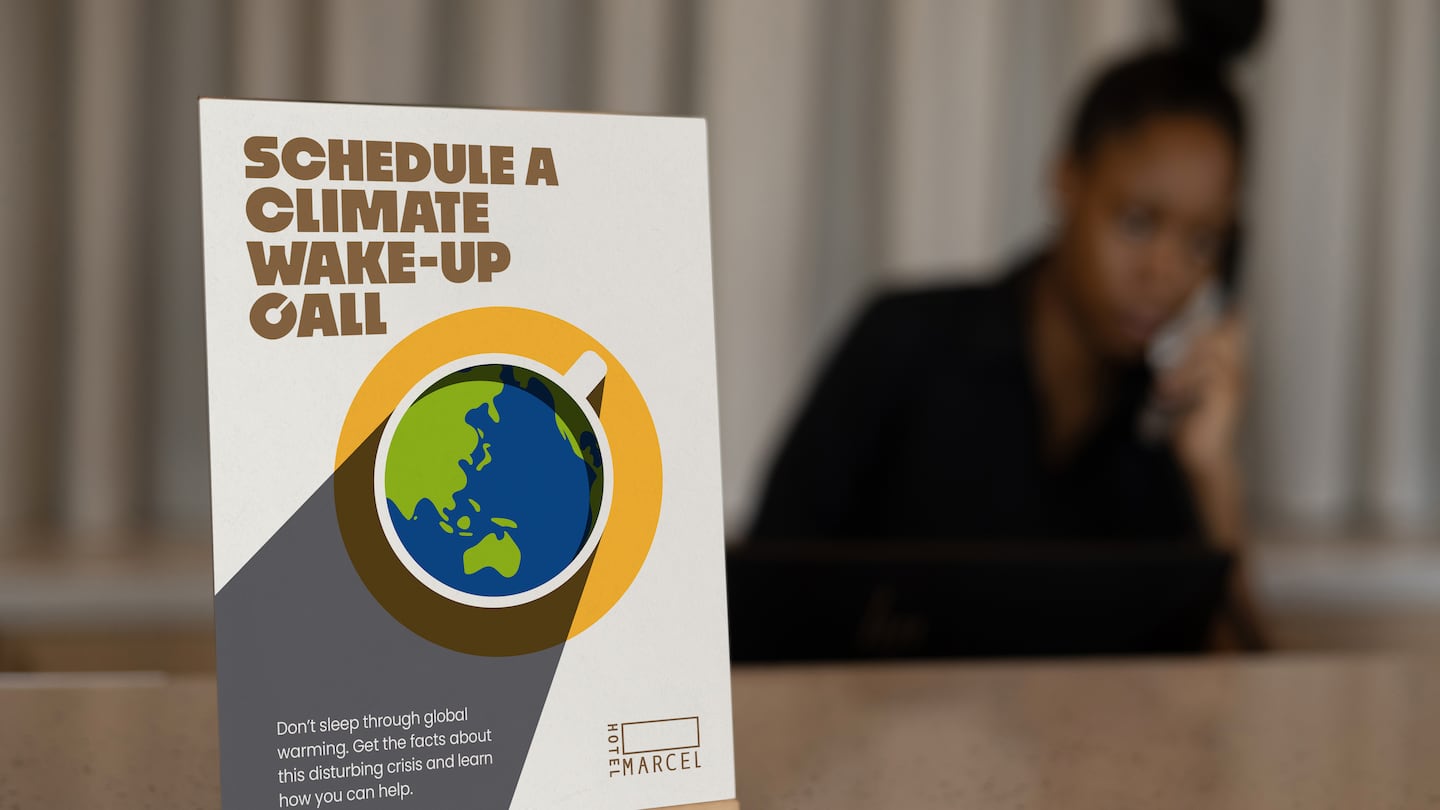 A sign announcing the new climate wake-up call at Hotel Marcel, touted as the country's first fossil-fuel-free hotel, rests on the hotel check-in counter.